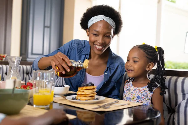Afroamericana Sonriente Madre Vertiendo Miel Panqueques Mientras Desayuna Con Hija — Foto de Stock