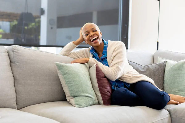 幸せなアフリカ系アメリカ人女性のソファに座って カメラを見て笑顔の肖像画 家庭だけで質の高い時間を過ごす 国内生活とライフスタイルの概念 — ストック写真
