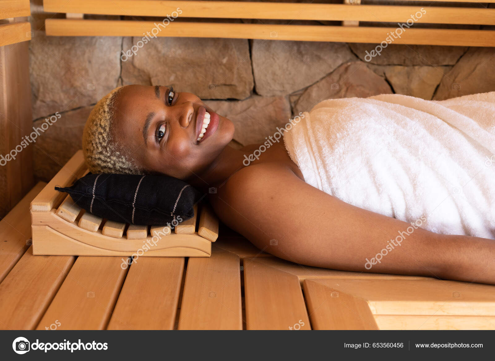 Young Woman in Towel Relaxing on Bench in Sauna Stock Photo