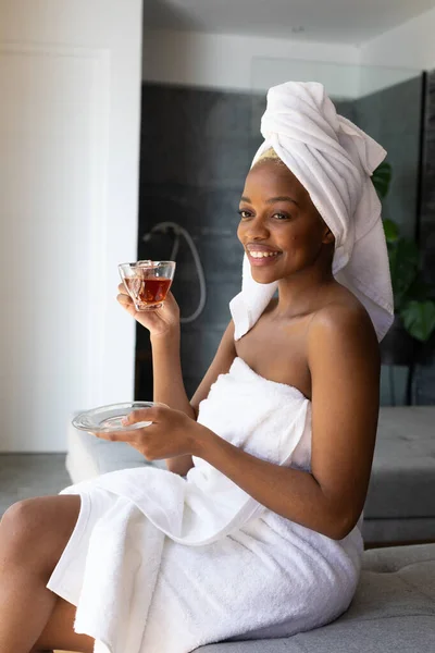 Χαρούμενος Αφροαμερικάνος Που Φοράει Πετσέτα Και Κρατάει Ένα Φλιτζάνι Τσάι — Φωτογραφία Αρχείου
