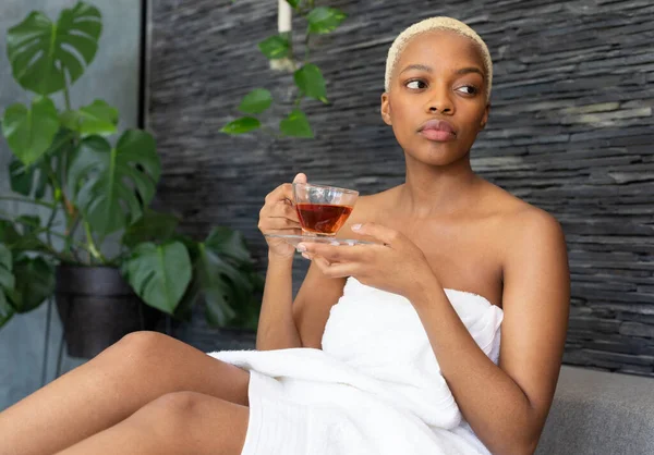 非洲裔美国人穿着毛巾 在浴室里端着一杯茶 独自待在家里的质量时间 家庭生活和生活方式概念 — 图库照片