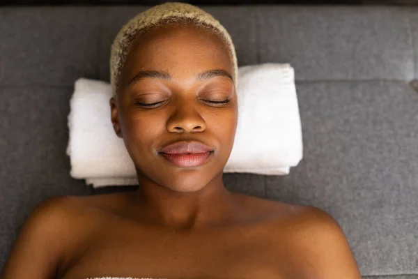 快乐的非洲裔美国女人闭着眼睛躺在毛巾上 美感和生活方式概念 — 图库照片