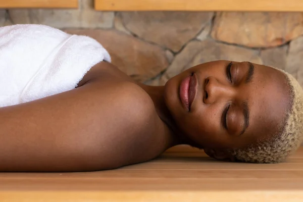Feliz Mulher Afro Americana Vestindo Toalha Deitada Sauna Spa Relaxamento — Fotografia de Stock