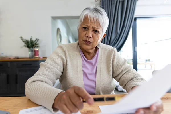 一位身材高大的老妇人一边看着相机 一边分析桌子上的账单 坐在家里 复制空间 生活方式 家庭财政 预算和退休概念 — 图库照片