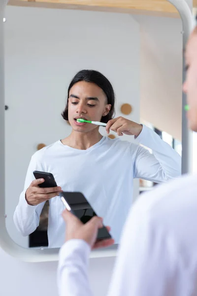 Szczęśliwy Dwurasowy Człowiek Myjący Zęby Korzystający Smartfona Łazience Spędzanie Czasu — Zdjęcie stockowe