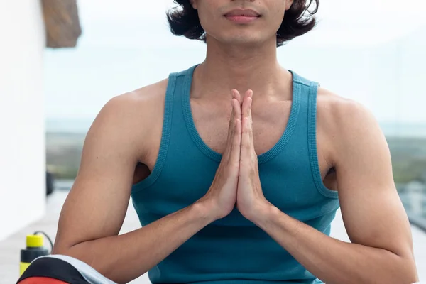 stock image Happy biracial man doing yoga, meditating on balcony. Spending quality time at home alone, domestic life and lifestyle concept.