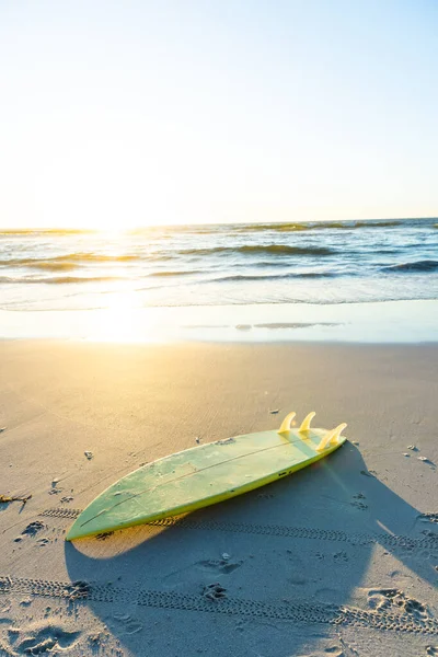 背景に澄んだ空に対して海の景色を望む砂浜の黄色のサーフボード コピースペース 変更されていない ウォータースポーツ 日没と休日の概念 — ストック写真
