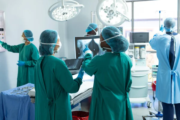 Rückansicht Zweier Unterschiedlicher Chirurginnen Die Operationssaal Mit Kollegen Über Röntgenbilder — Stockfoto