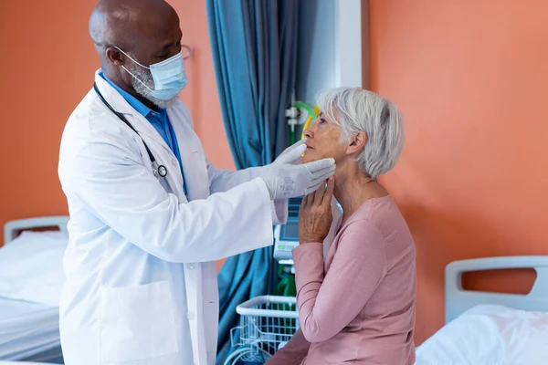 Mengalihkan Dokter Senior Pria Bertopeng Wajah Memeriksa Tenggorokan Pasien Wanita — Stok Foto