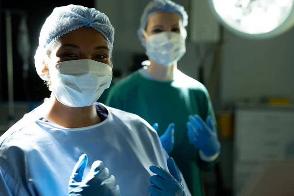 Portret Uśmiechniętej Dwurasowej Chirurżki Czapce Masce Sali Operacyjnej Kolegą Usługi — Zdjęcie stockowe