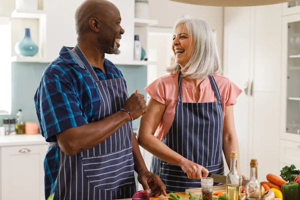 Ευτυχισμένο Ζευγάρι Ηλικιωμένων Που Φορούν Ποδιές Και Μαγειρεύουν Στην Κουζίνα — Φωτογραφία Αρχείου