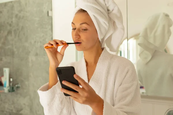 Heureuse Femme Caucasienne Portant Peignoir Brossant Des Dents Utilisant Smartphone — Photo