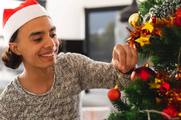 Gelukkige Biracial Man Met Kerstmuts Kerstboom Versieren Woonkamer Kwaliteitstijd Alleen — Stockfoto