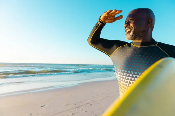 在海滩上微笑着 秃头的非洲裔美国老人捂住双眼 背着冲浪板冲向天空 — 图库照片