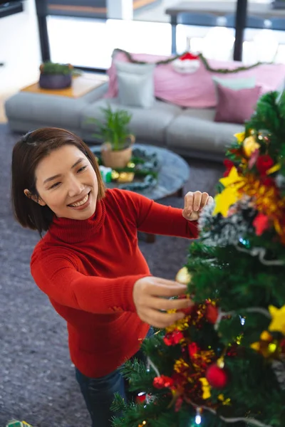 Ευτυχισμένη Ασιάτισσα Που Στολίζει Χριστουγεννιάτικο Δέντρο Στο Σαλόνι Περνάμε Ποιοτικό — Φωτογραφία Αρχείου