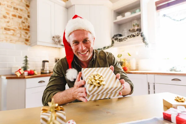 快乐的高加索人 戴着桑塔帽 坐在厨房的餐桌旁 并有视频通话 圣诞时独自在家度过美好的时光 — 图库照片