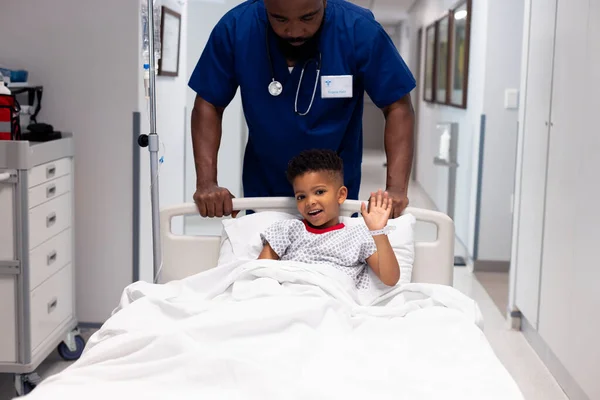 Afro Amerikaanse Mannelijke Dokter Duwt Zwaaiende Jongen Patiënt Het Ziekenhuis — Stockfoto
