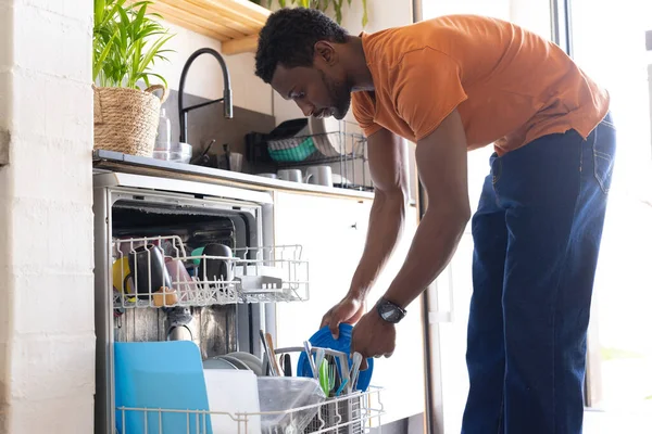 Mutlu Afro Amerikan Adam Mutfakta Durup Bulaşık Makinesini Boşaltıyor Evde — Stok fotoğraf