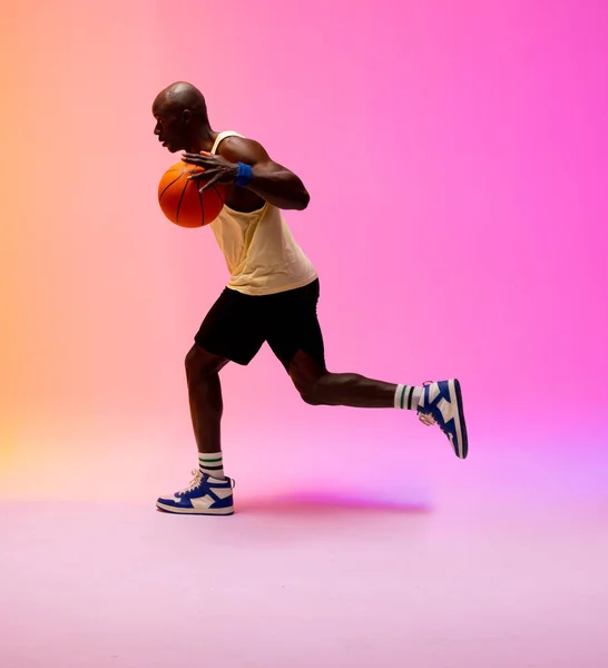 Obraz Afrykańskiego Amerykańskiego Koszykarza Biegającego Koszykówką Różowym Pomarańczowego Tle Koncepcja — Zdjęcie stockowe