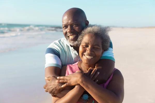 Šťastný Afroameričan Starší Muž Objímající Ženu Zezadu Užívající Pláži Proti — Stock fotografie