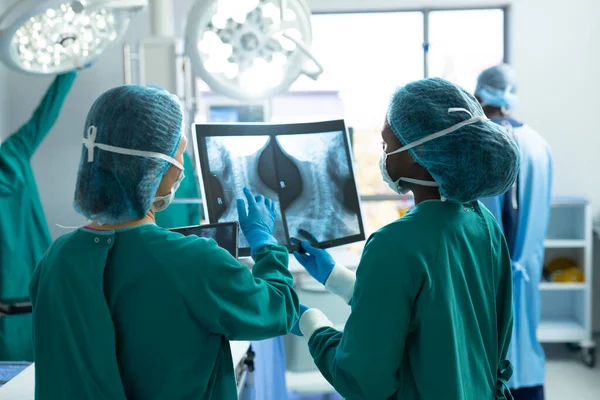 Vue Arrière Deux Chirurgiennes Diverses Discutant Radiographie Salle Opération Avec — Photo