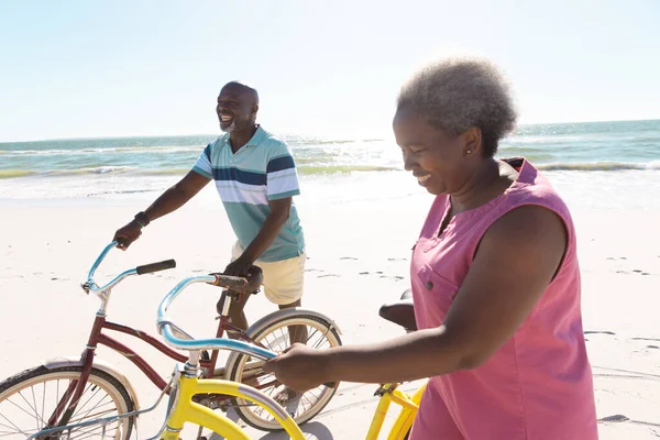 Sorrindo Casal Sênior Afro Americano Com Bicicletas Andando Praia Contra — Fotografia de Stock