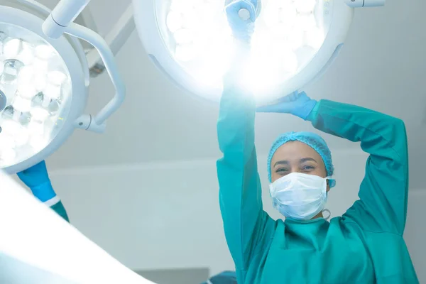 在手术室里为手术调整灯光时 微笑的分娩女外科医生 并留有复制空间 医疗和保健服务 — 图库照片