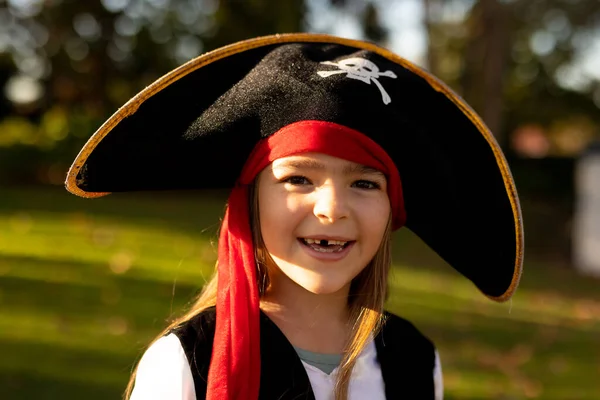 Image of happy caucasian girl in pirate costume in autumn garden. Halloween, american culture and celebration concept.