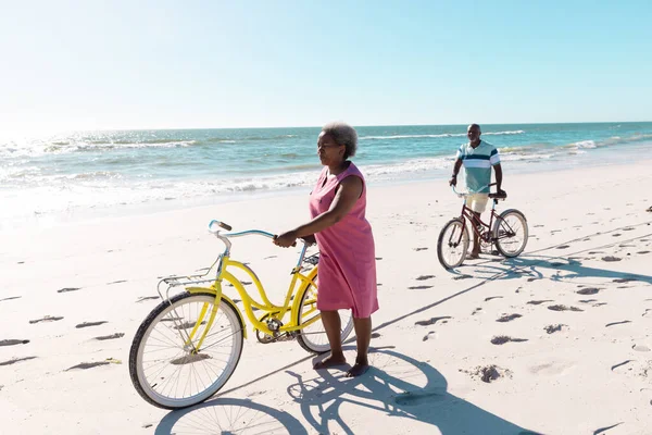 アフリカ系アメリカ人のシニアカップルで 夏は海と澄んだ空に向かって砂浜を自転車で歩く コピースペース 変更されていない 一緒に 自然とアクティブなライフスタイル — ストック写真