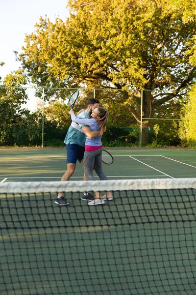 快乐的高加索夫妇在室外网球场打网球拥抱 健康爱好 健身和闲暇时间概念 — 图库照片