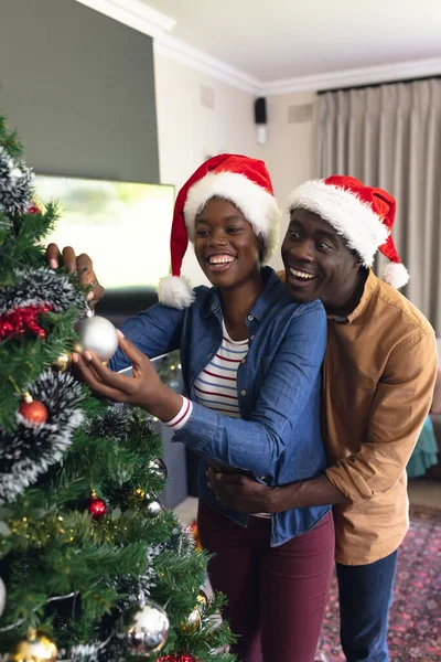 非洲裔美国人夫妇花时间在一起装饰圣诞树的纵向图片 圣诞节 家庭时间和庆祝概念 — 图库照片
