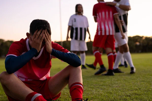 Multirazziale Triste Giocatore Calcio Maschile Con Testa Mano Seduto Terreni — Foto Stock