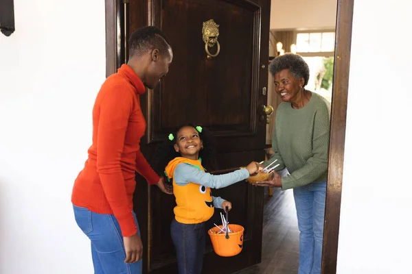 アフリカ系アメリカ人の母親と娘が お年寄りのお菓子を持ってハロウィンの衣装で登場します ハロウィン アメリカ文化 お祝いのコンセプト — ストック写真