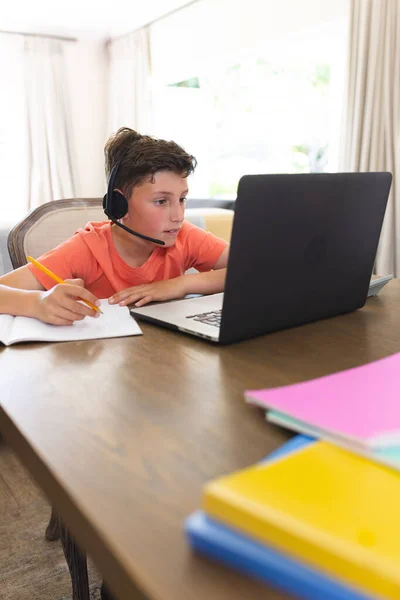 在客厅里用笔记本电脑和耳机学习和使用高加索男孩的垂直图片 家庭教育 远距离教育 — 图库照片