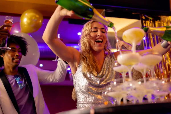幸せな白人女性がナイトクラブで多様な友人とグラスにシャンパン噴水を注ぐ 楽しさ 飲み物 包括性とパーティーのコンセプト — ストック写真