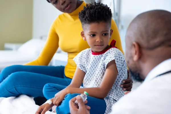 非裔美国男医生拿着疫苗与男病人交谈 与母亲交谈 医疗和保健服务 — 图库照片