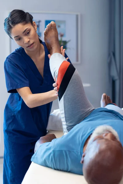 Vertikální Různorodý Ženský Fyzioterapeut Léčící Nohu Staršího Muže Kopírující Prostor — Stock fotografie