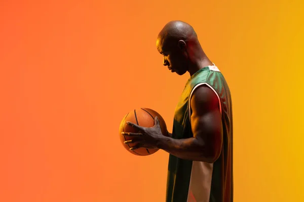 Obrázek Afrického Amerického Basketbalisty Basketbalem Neonově Oranžovém Pozadí Sportovní Soutěžní — Stock fotografie