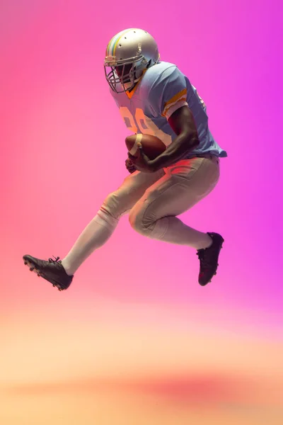 アフリカ系アメリカ人の男性アメリカンフットボール選手はネオンピンクの照明でボールを保持する スポーツ トレーニング アクティブなライフスタイルの概念 — ストック写真