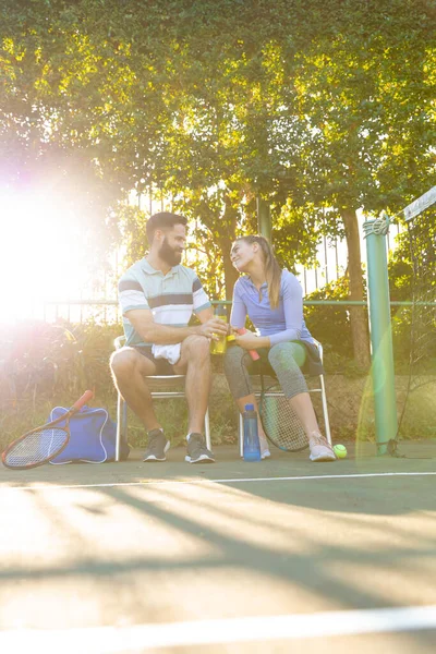 屋外テニスコートの横で話している椅子に座ってテニスをしている幸せな白人夫婦 スポーツ 健康的な趣味 フィットネス 余暇時間の概念 — ストック写真