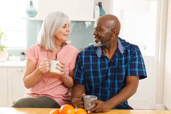 キッチンでコーヒーを飲む幸せなシニア多様なカップル 家庭や退職のコンセプトで質の高い時間を過ごす — ストック写真