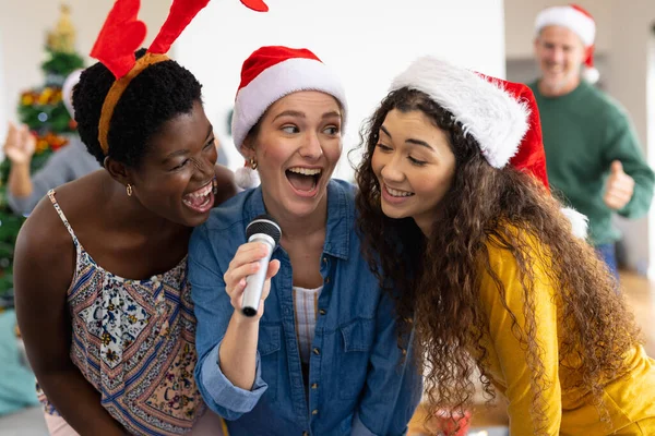ホーム歌カラオケでクリスマスを祝う幸せな多様な女性の友人のイメージ クリスマス お祝い 包括性とライフスタイルの概念 — ストック写真