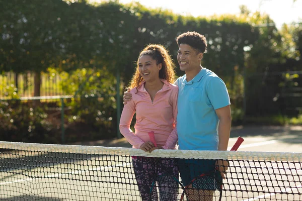Χαμογελαστό Ζευγάρι Που Παίζει Τένις Αγκαλιάζοντας Ηλιόλουστο Υπαίθριο Γήπεδο Τένις — Φωτογραφία Αρχείου