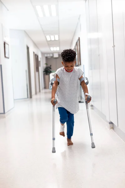 非洲裔美国男孩患者的垂直行走与拐在医院走廊与复制空间 医疗和保健服务 — 图库照片