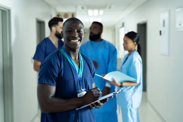 Meşgul Hastane Koridorunda Yazan Gülümseyen Afro Amerikan Erkek Sağlık Görevlisinin — Stok fotoğraf