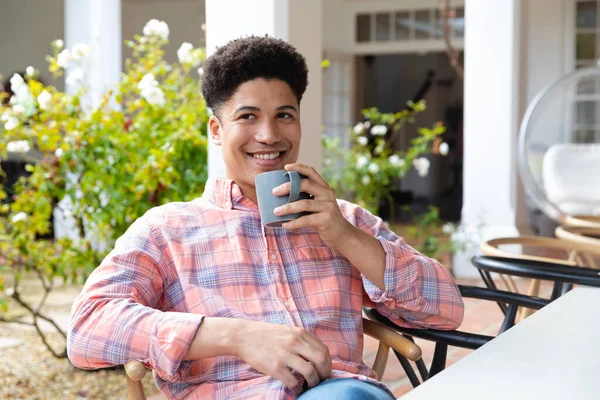 Szczęśliwy Dwurasowy Mężczyzna Siedzący Tarasie Ogrodowym Pijący Kawę Przed Domem — Zdjęcie stockowe