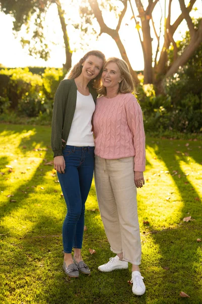 秋の庭でカメラを向ける幸せな白人の母親と大人の娘の垂直画像 家族と一緒に質の高い時間を過ごすコンセプト — ストック写真