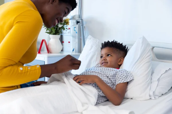 快乐的非洲裔美国母亲与儿子一起坐在病床上 带着复制空间微笑 医疗和保健服务 — 图库照片