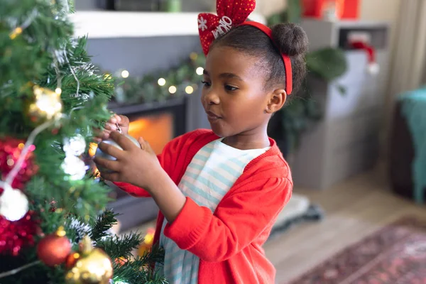 リビングルームでクリスマスツリーを飾るアフリカ系アメリカ人の女の子 クリスマス 子供時代 お祝いのコンセプト — ストック写真