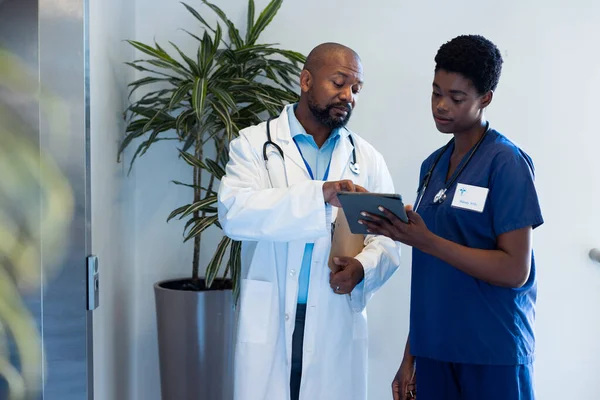 アフリカ系アメリカ人の男性と女性の医師は コピースペースのある病院の廊下でタブレットを見ています 医療サービス — ストック写真